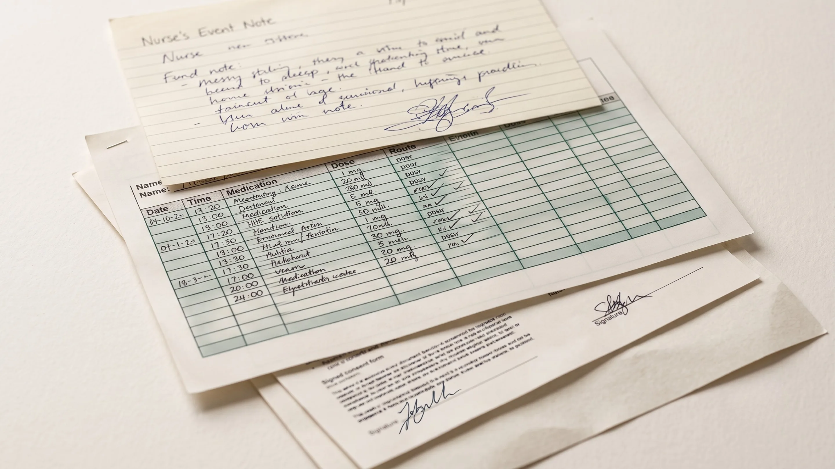 A handwritten nurse's event note resting on a signed medication chart, the handwriting on both hard to read